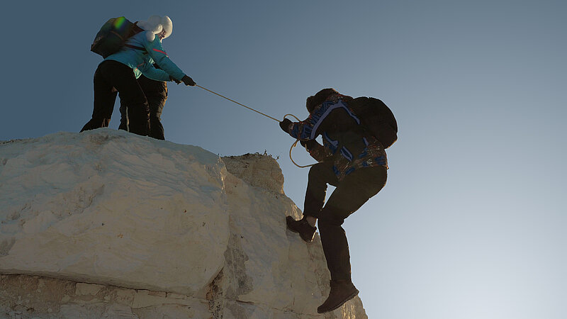 Zwei Bergsteiger erklimmen zusammen den Gipfel